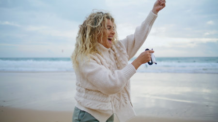 Romantic girl holding kite string at beautiful ocean view. Cheerful mother play enjoying family weekend on beach. Attractive blonde woman launching toy relax on date. Childhood memories games conceptの写真素材