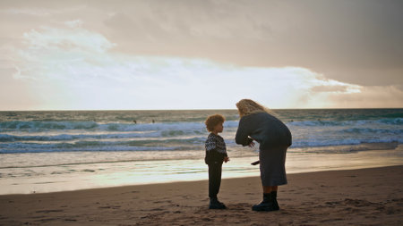 Parent scolding little boy on beach. Young mother talking boy resting shore on autumn weekend. Concerned woman babysitter teaching explaining disobedience to child. Upbringing motherhood concept.の写真素材