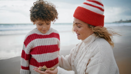 Caring mother kissing child on ocean beach closeup. Curly little son hugging mom on autumn seaside weekend. Single mom playing teaching kid enjoying vacation together. Parent love support concept.の写真素材