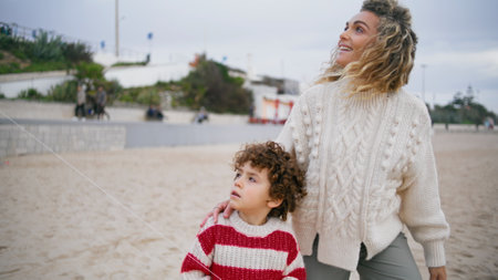 Mother son walking beach in spring. Loving family enjoying weekend outdoors. Adorable little boy holding kite toy thread go with babysitter. Smiling beautiful foster mom having fun together with childの写真素材