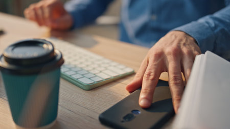 Businessman hands answering telephone call at cabinet closeup. Unknown man picking up mobile phone sitting at workplace. Anonymous freelancer holding smartphone looking on screen at office interiorの写真素材