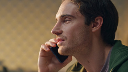 Cheerful businessman phone call speaking at office closeup. Happy positive freelancer communicating smartphone enjoying conversation at creative workplace. Smiling young man talking alone in cabinetの写真素材