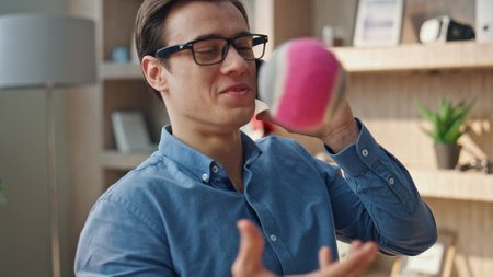 Calling freelancer tossing ball at office closeup. Happy cheerful businessman taking work break talking cellphone at workplace. Relaxed designer man communicating mobile phone playing indoors aloneの写真素材