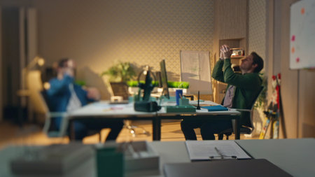 Chilling freelancers tossing ball playing at office blur effect. Relaxed man catching toy communicating with partner in friendly atmosphere break. Two colleagues resting together at hipster interiorの写真素材