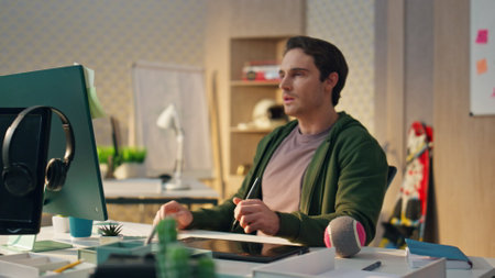Focused artist staring computer display in evening office. Closeup serious man analyzing design working at creative space interior. Thoughtful project designer looking screen sitting desk workplaceの写真素材