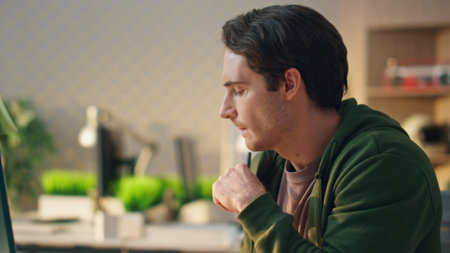 Pensive man watching computer display at modern office closeup. Designer holding stylus looking for ideas at ecological apartment. Freelance artist drawing hand graphic tablet at design studio aloneの写真素材