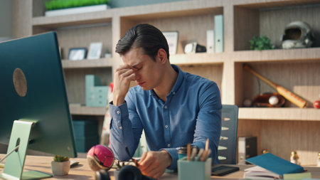 Tired professional working office rubbing eyes. Unmotivated manager having break trying rest at modern workplace. Overworked man stretching hands feeling discomfort. Yawning guy taking off eyeglassesの写真素材