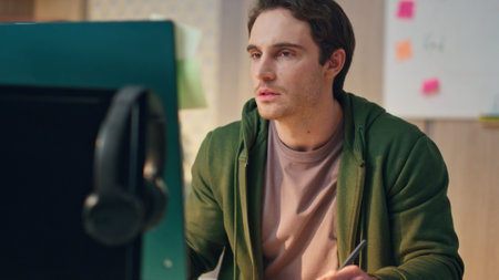 Pensive freelancer drawing tablet at modern office closeup. Attentive graphic designer holding colour samples watching computer screen at workplace. Man creator comparing with monitor creating aloneの写真素材