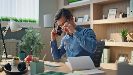 Angry businessman calling phone sitting at work desk closeup. Nervous executive manager discussing company problems on telephone conversation. Man worker feeling stress yelling at creative officeの写真素材
