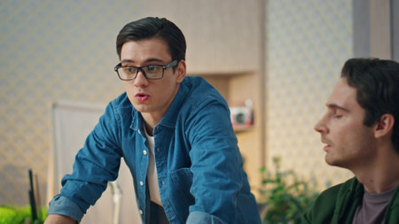 Creative businessmen discussing project at informal office closeup. Two guys staring computer screen talking to each other. Eyeglasses man communicating with colleague at workplace. Teamwork conceptの写真素材