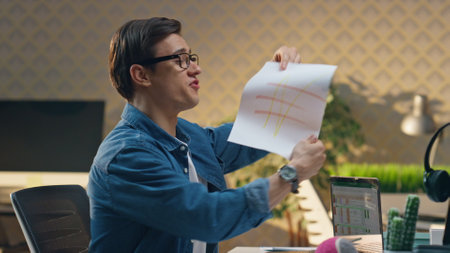 Carefree guys joking together at office room closeup. Excited man showing sketch throwing crumpled paper at partner. Happy colleagues having fun at creative interior place. Two freelancers playingの写真素材