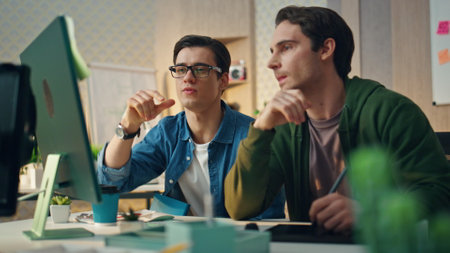 Focused colleagues staring computer screen at room. Closeup creative men team work together analyzing project results. Serious mentor entrepreneur help teaching office trainee. Business cooperationの写真素材