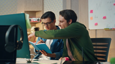 Startup guys discussing notebook flipping pages at modern office. Closeup creative business team having video call using desktop computer in room. Designers couple presenting project together onlineの写真素材