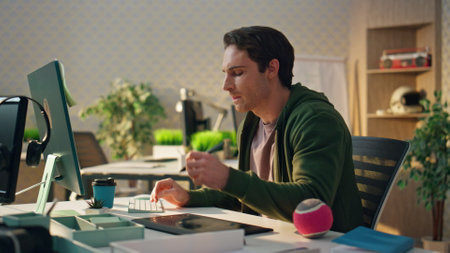 Pensive creator watching computer screen at modern office. Closeup graphic designer holding ball looking ideas at ecological flat. Freelance man using stylus creating at tablet. Design studio conceptの写真素材