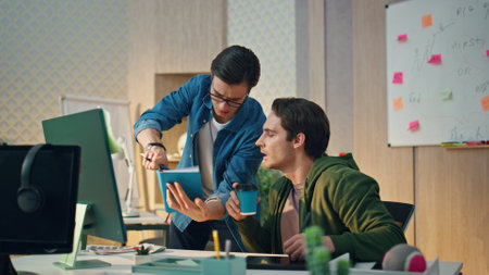 Smart startupers looking computer brainstorming at office. Eyeglasses creator man writing notes. Two...