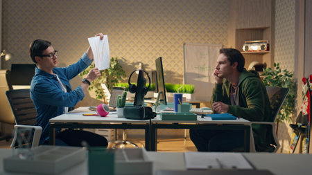 Business coworkers discussing project together at office. Critical man creator declining ideas crumpling paper at computer workplace. Two startupers guys brainstorming at hipster sunny apartmentsの写真素材