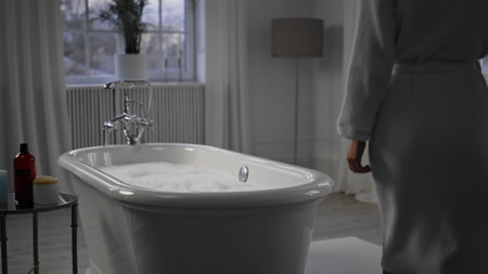 Unknown lady walking bathroom closeup. Satisfied woman sitting bathtub touching foam at cozy home....