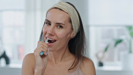 Pov cheerful model brushing mouth at bathroom. Close up happy woman holding toothbrush enjoying morning dental care routine in bath. Portrait fresh lady cleaning teeth having daily procedures at homeの写真素材