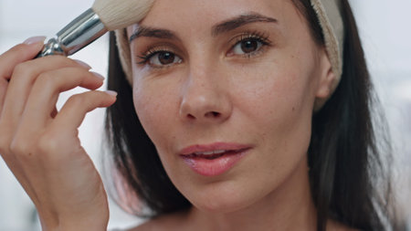 Smiling model applying powder at bath portrait. Beauty influencer girl preparing makeup recording blog pov video view. Young woman holding brush putting cosmetics attentively closeup. Visage conceptの写真素材