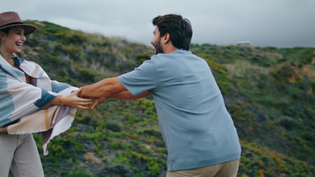 Excited happy couple enjoy walk on beautiful ocean coast cloudy summer day. Loving young people holding by hands relaxing on nature. Smiling attractive woman following bearded man to scenic sea shore.の写真素材
