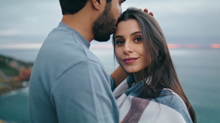 Cute lovely couple relaxing on coast gloomy evening closeup. Relaxed tranquil pair standing in front gray beautiful ocean. Attractive bearded man hugging tender woman on romantic weekend. Love conceptの写真素材