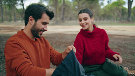 Cheerful cute family couple sitting picnic at beautiful autumn forest close up. Smiling man giving food to attractive woman. Happy pair relaxing sitting blanket on nature. Weekend together concept.の写真素材