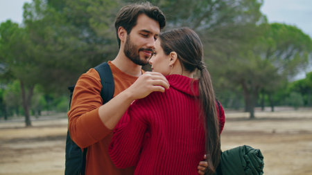 Two lovely hikers hugging standing on cloudy nature with backpacks close up. Tender couple in love embracing at beautiful autumn forest. Happy cute travelers relax on hike enjoying feelings closeness.の写真素材