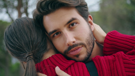 Closeup handsome bearded man hugging young woman on nature. Attractive guy embracing lovely girl outdoors looking camera. Happy couple feeling love tenderness enjoy romantic date. Relationship conceptの写真素材