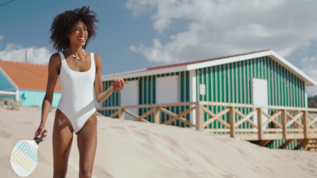 Beach tennis girl playing practicing on sunny day. Slim attractive player enjoy game having fun at seashore. Beautiful african american hitting ball resting on summer vacation. Weekend hobby concept.の写真素材