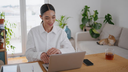 Friendly businesswoman greeting computer videocall at home office. Close up positive student girl waving hand looking laptop screen at table. Cheerful woman studying online talking teacher at callの写真素材