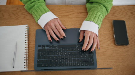 Unrecognizable woman working laptop in home office close up. Lady hands typing computer scrolling touchpad alone indoors. Unknown businesswoman searching information in internet using modern deviceの写真素材