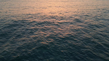Closeup sea water surface reflecting morning sky. Drone view calm ocean rippling zoom on. Deep marine lapping at sunrise dawn super slow motion. Tranquil waves moving slowly. Nature beauty backgroundの写真素材