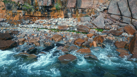 Foamy ocean rocky cliff washing closeup. Powerful stormy sea surf crashing high stoned mountain. Rough waves creating water explosion breaking on dangerous brown rocks. White swell splashing at coastの写真素材