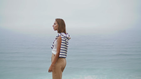 Ocean girl listening music at beautiful marina view. Attractive woman relaxing looking camera outdoors. Pensive carefree student enjoying podcast walking seashore on weekend. Calm morning concept.の写真素材