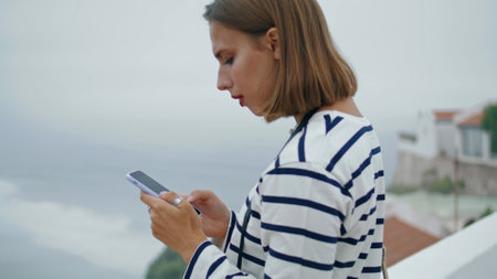 Tourist blogger make photos seaside town closeup. Beautiful girl use smartphone taking vacation...