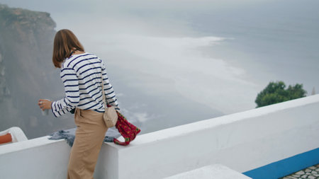 Girl resting sea town rooftop on summer holidays. Stunning mediterranean coast. Beautiful tourist student leaving viewpoint exploring city alone. Pensive pretty woman photographer walking old village.の写真素材