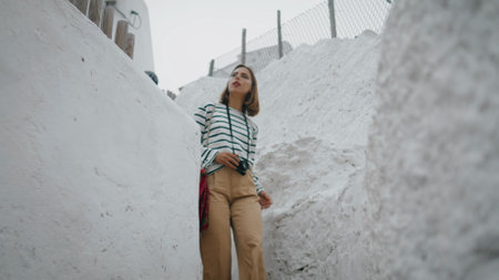 Girl walk white street in old mediterranean city. Travel blogger making photos enjoying southern architecture. Beautiful woman student taking pictures stroll on summer vacation. Exploring town conceptの写真素材