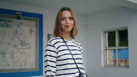 Girl posing bus stop closeup. Beautiful smiling tourist waiting public transport in old european town. Relaxed woman looking camera enjoying summer weekend trip. Rural transportation tourism concept.の写真素材