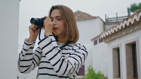 Girl taking old camera photos at whitewashed houses. Beautiful tourist travel mediterranean city...