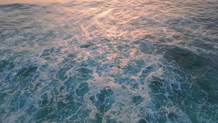 Stunning foamy sea water splashing on seashore stones super slow motion. Aerial view stormy blue waves rolling dark coastal rock making white foam. Powerful ocean washing shoreline. Marine landscapeの写真素材