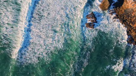 Top view waves barrelling to volcanic cliffs in super slow motion. Drone shot beautiful powerful sea...