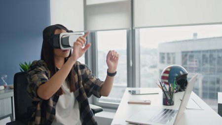 Headset woman examining VR technologies at city view flat. Creative game designer working augmented reality in blue wall office closeup. Focused freelancer testing 3d program alone. High-tech conceptの写真素材