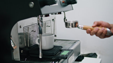 Unknown barista putting portafilter in coffee machine for making hot drink close up. Man hand inserting filter with grinded coffee beans in espresso device. Preparing delicious caffeine beverage.の写真素材