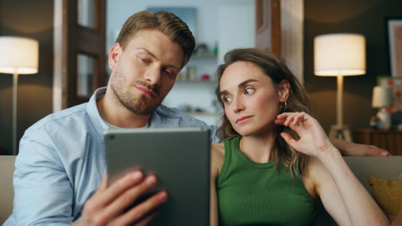 Upset pair talking tab call at living room closeup. Sad embracing couple communicating relatives looking pad computer zoom on. Depressed partners video calling saying bad news at distance conversationの写真素材