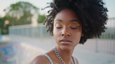 Stylish fashion model posing at evening urban street close up. Gorgeous african american girl with bright makeup looking camera smiling. Beautiful female teen face with perfect skin. Beauty concept.の写真素材