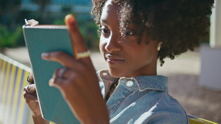 Girl reader enjoy book sitting sunny summer street close up. Beautiful african american teenager...
