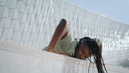 Contemporary choreographer practicing at abstract building. African american man showing flexible jazz dance at urban settings. Dreadlocks sportsman training outdoors. Active dancer improvisingの写真素材