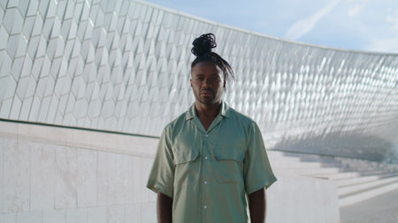 Modern dancer looking camera outdoors zoom on. Brown skin man posing at urban open space stadium alone. Contemporary african american guy relaxing after training. Young choreography artist conceptの写真素材