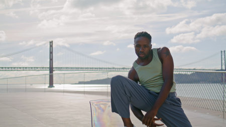 Inspired man doing performance rehearsal at water view. Freedom guy training contemporary dance moves closeup. African american dancer practicing freestyle sea place. Artistic performer looking cameraの写真素材