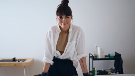 Smiling tattoo artist looking camera at home studio zoom on. Happy woman leaning couch posing at workplace portrait. Cheerful tattooist feeling joyful staring lens alone close up. Creative occupationの写真素材